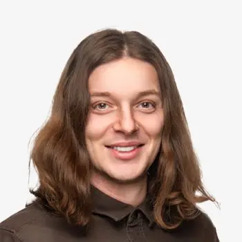 Close-up of a cheerful man with long hair and a friendly smile.