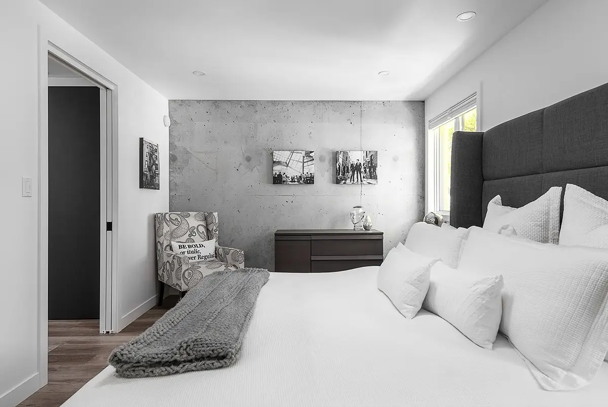 Bright contemporary bedroom with white walls and concrete accent wall.