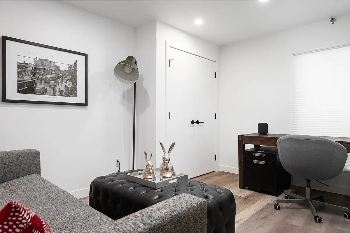 Bright minimalist home office with gray office chair and black desk setup.