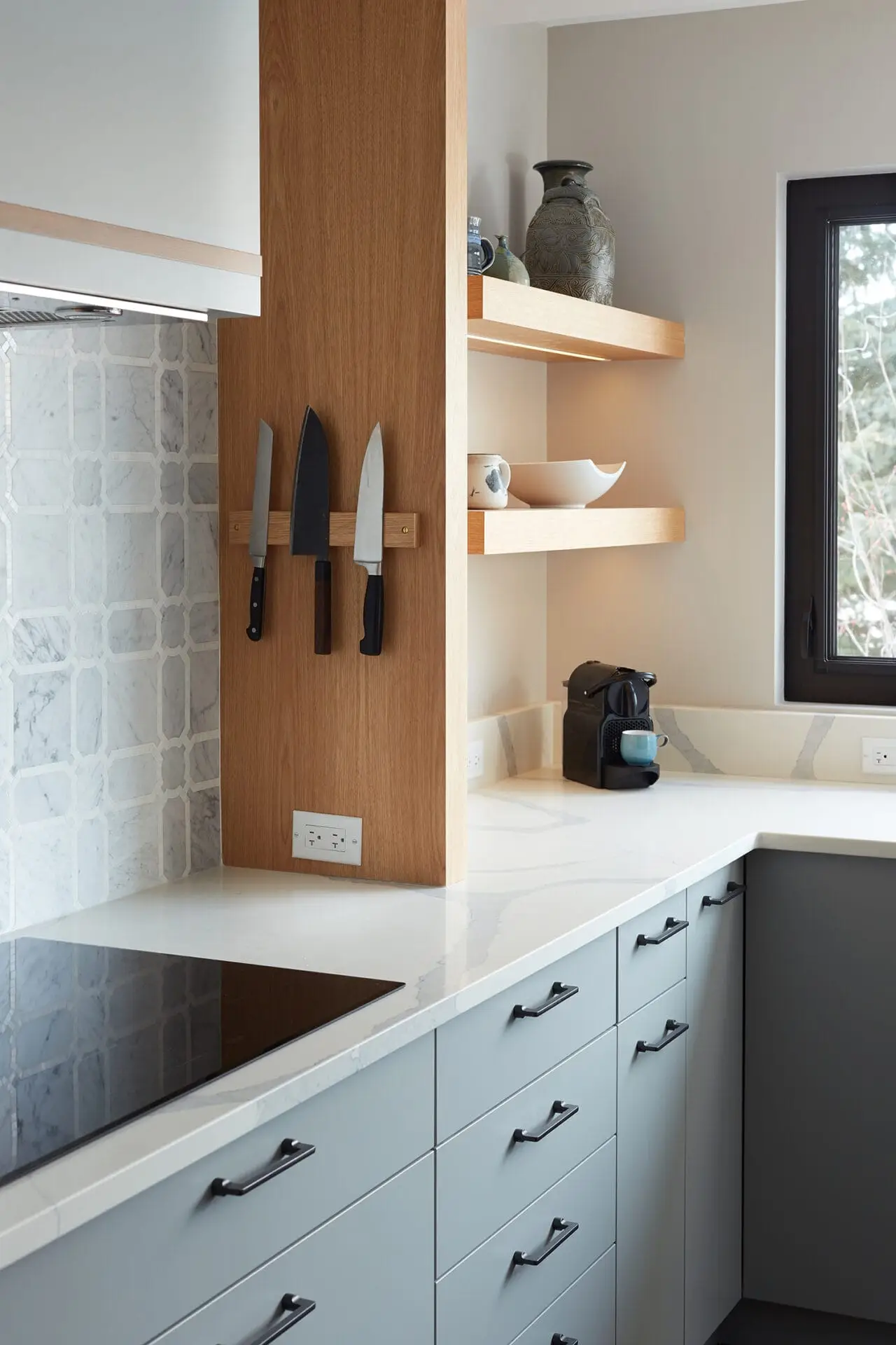 Kitchen knife set on wooden wall mount with marble backsplash and natural light.