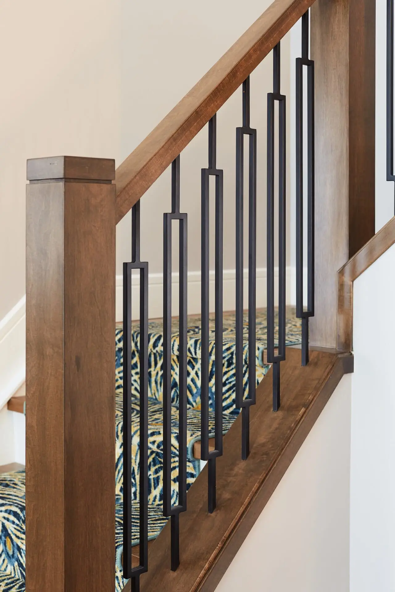 Modern staircase featuring a wooden handrail and stylish black metal balusters.
