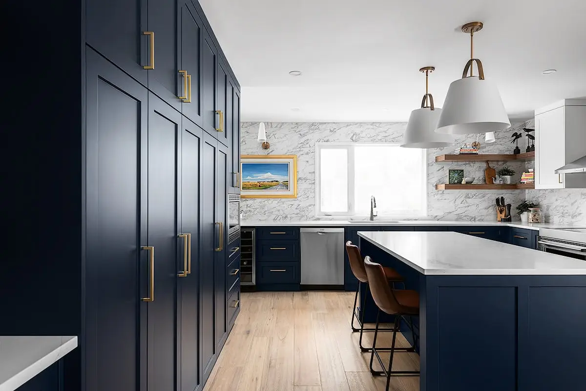 Beautiful navy kitchen with marble countertops, hanging pendant lights, and wooden accents.