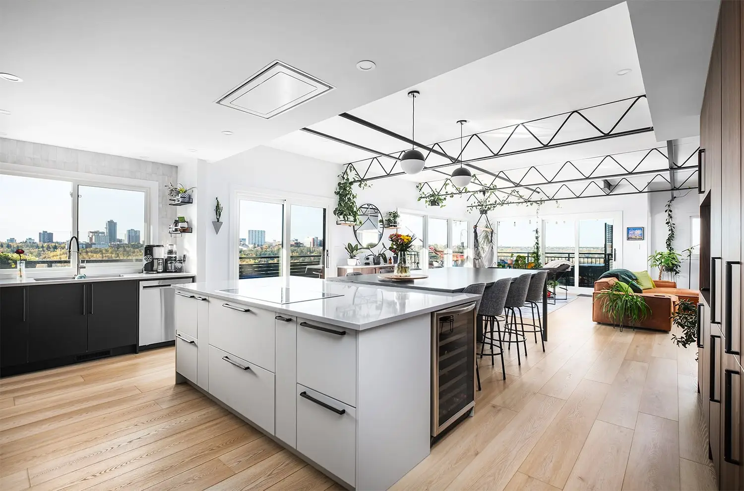 Bright, airy kitchen with large windows, contemporary decor, and greenery accents.