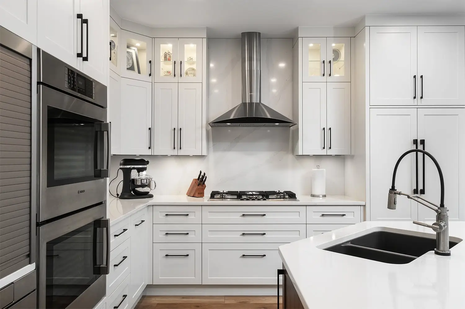 Bright white kitchen with modern cabinetry, stainless steel oven, and sleek black fixtures.