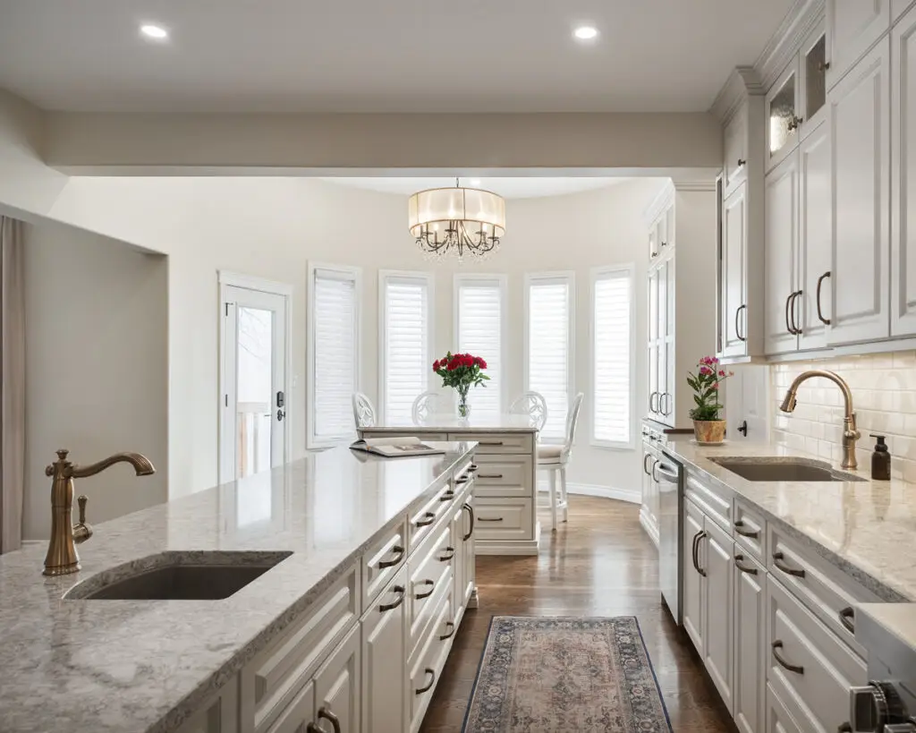 Bright, contemporary kitchen featuring white cabinetry, granite counters, and stylish lighting fixtures.