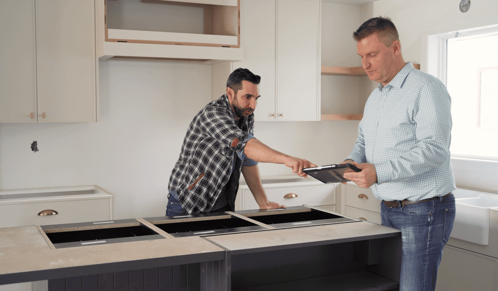 Ben Guittard (Owner) in a kitchen with a Real Estate Agent pointing to a tablet discussing renovation plans on behalf of a client.